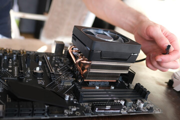 hands of young male master install cooler with copper heat pipes for the processor, other parts of pc into case, the concept of repairing equipment, assembling, upgrading a personal computer