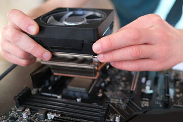hands of young male master install cooler with copper heat pipes for the processor, other parts of pc into case, the concept of repairing equipment, assembling, upgrading a personal computer