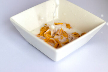 Milk being poured in to the white bowl with cereal in it. Food