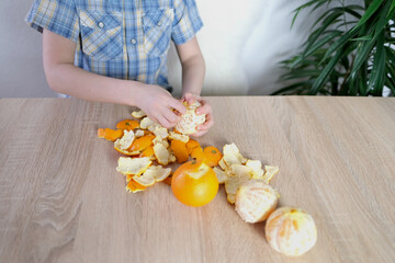 child, boy 6-8 years old peels big orange oranges, the concept of the development of fine motor skills, patience, healthy food, healthy baby food