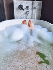 Two legs of girl in the bathtube with bubbles