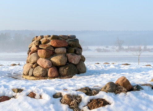 Stone altar near the frozen river in cold sunny winter morning.