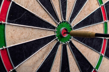 Side view of darts board and arrow hitting bullseye.