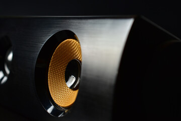 Close up of yellow audio woofer at dark background.