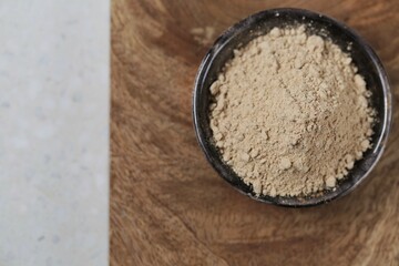 Guarana powder in a  ceramic plate on a wooden board on a gray marble background.Natural energetic. Portion of Guarana Powder.