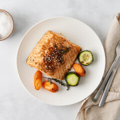Ketogenic dinner with fish. Fillet of salmon with vegetables on white plate - zucchini, carrots. Healthy diet food, keto diet, Mediterranean cuisine. Top view