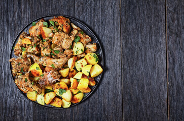 braised Rabbit with potatoes on a black plate