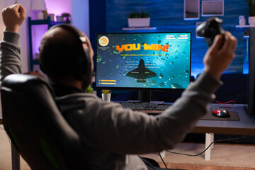 Addicted man playing space shooter videogame using headphones and wireless console. Excited gamer...