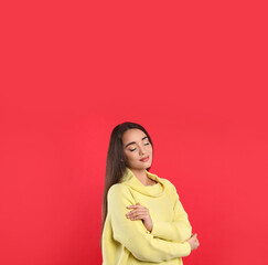 Fototapeta premium Beautiful young woman wearing yellow warm sweater on red background