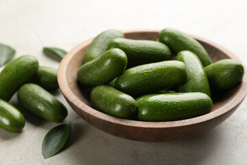 Wooden bowl with seedless avocados on grey table, closeup