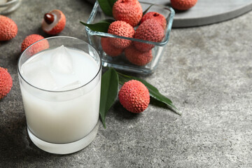 Lychee juice and fresh fruits on grey table. Space for text