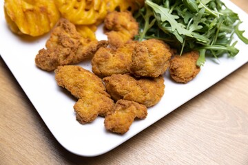 Chicken nuggets with salad on table closeup
