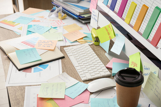 Computer, notes and office stationery in mess on desk. Overwhelmed with work