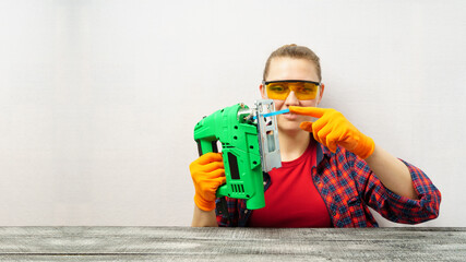 Beautiful girl with an electric jigsaw on a white background with copy space.