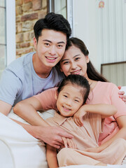 A happy family of three is sitting on the sofa in the living room