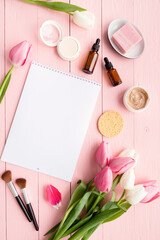 Obraz na płótnie Canvas Top view of cosmetics and pink and white tulips with calendar or notepad for mock up flat lay on pink wooden background