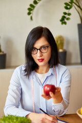 Nutritionist, dietitian woman at the office, hold apple in the hand