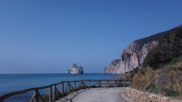 Walking down to the beach in a sunny day in summer. Landscape of Sardinian island sea with azure water, sandy bottom at sunset. Pan di Zucchero, Masua