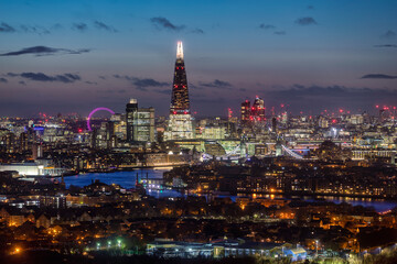 Elevated view to the illuminated, urban skyline of London, UK, along the river Thames during evening