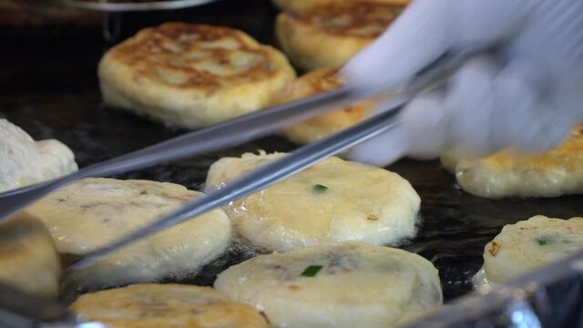 Process of cooking Korean Hotteok doughnut in an oily frypan in street market close-up