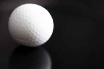 White golf ball somewhat out of focus on dark background