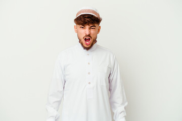 Young Arab man wearing the typical arabic costume isolated on white background screaming very angry and aggressive.