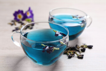 Obraz na płótnie Canvas Glass cups of organic blue Anchan on white wooden table, closeup. Herbal tea