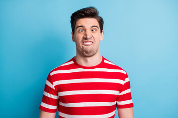 Photo portrait of silly comic man grimacing fooling in striped t-shirt isolated on bright blue...