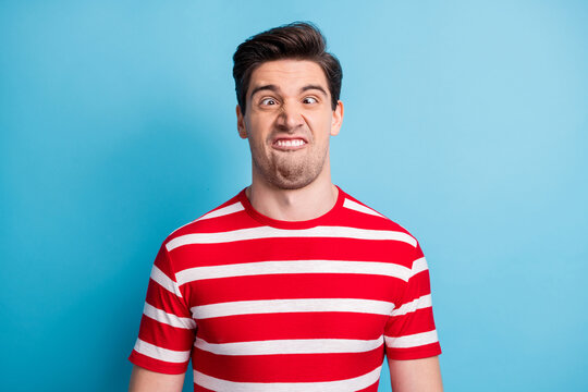Photo portrait of silly comic man grimacing fooling in striped t-shirt isolated on bright blue color background