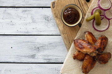 Fried chicken wings with vegetables and sauce on wooden background