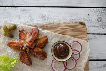 Fried chicken wings with vegetables and sauce on wooden background