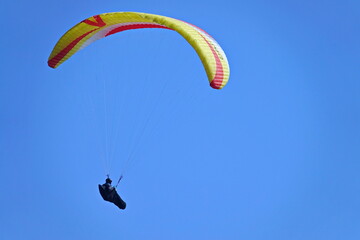 Paragliding. Extreme sport. Paraglider silhouette flying in the blue sky.