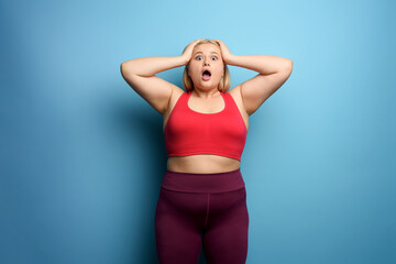Fat girl in fitness suite wants to start a diet but has some. Cyan background