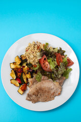 fried meat with salad and vegetables on white plate