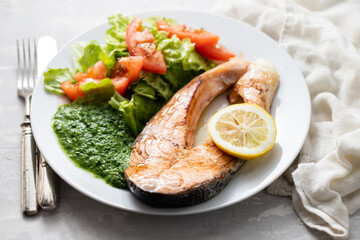 fried salmon with spinach and salad on white plate