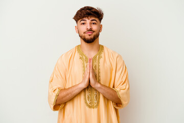 Young Moroccan man isolated on white background praying, showing devotion, religious person looking...