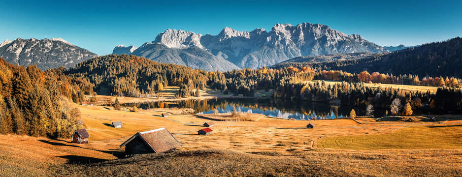 Stunning Autumn landscape. Panoramic view of mountain scenery in the Alps with alpine meadows, colorful trees in forest and majestic Karwendel mountains on background. Geroldsee. Bavaria, Germany
