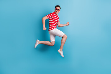 Fototapeta na wymiar Full length body side profile photo happy man jumping high running fast isolated on vibrant blue color background