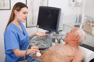 Female doctor using ultrasound scan examining male patient in modern hospital