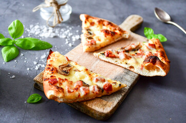 Slice of  home made italian  pizza carbonara on a wooden table