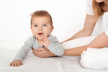 Mother holding cute happy baby boy with beautiful blue eyes on white background