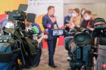 Cameras recording businessman delivering speech to journalists