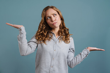 Portrait of a pretty confused woman shrugging shoulders