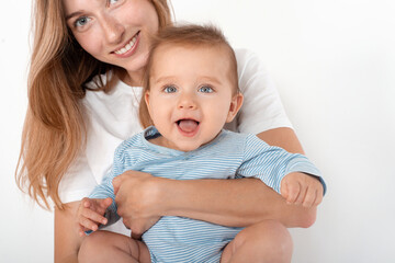 Mother holding cute happy baby boy with beautiful blue eyes on white background