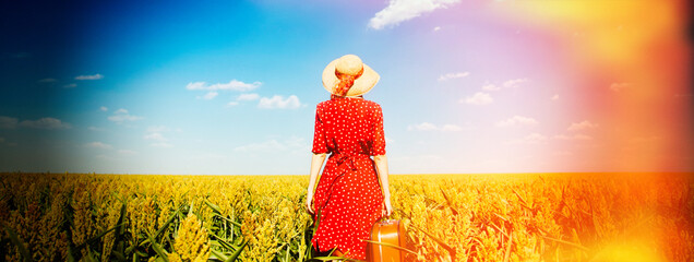 Redhead girl with suitcase at corn field.