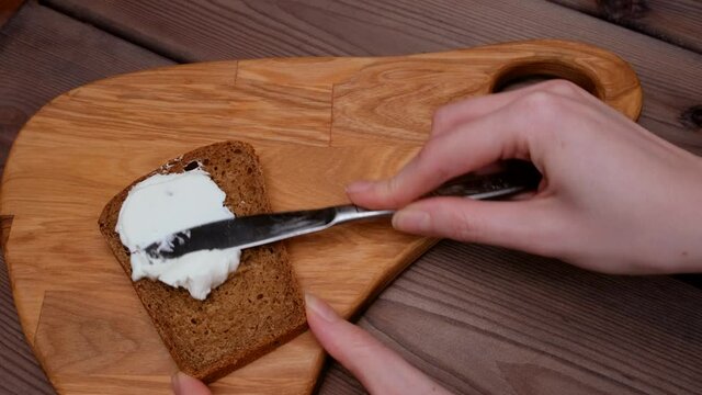 A woman's hand spreads butter on a slice of bread. Flat ley. Making a breakfast sandwich