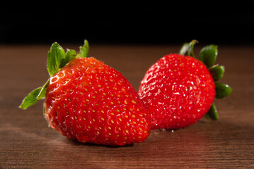 Strawberries, details of two strawberries on the table, black background, selective focus.