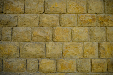 Modern yellow stone brick wall background close-up. Copy space. Natural. Building exterior	
