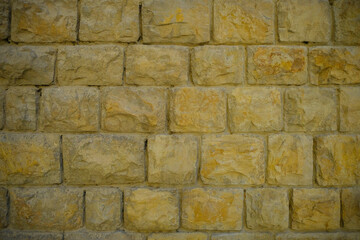 Modern yellow stone brick wall background close-up. Copy space. Natural. Building exterior	
