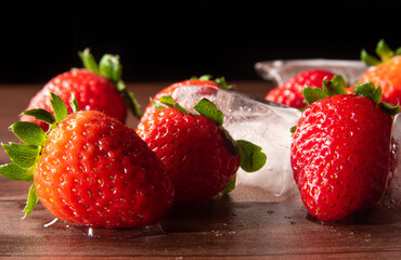 Strawberries, beautiful details of strawberries and ice cubes on a table, black background, selective focus.